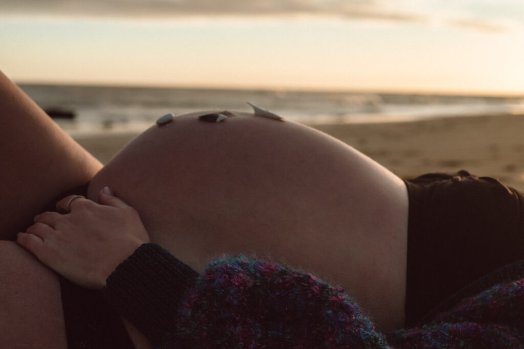 Bump shoot with pregnant mother on the beach for professional pregnancy shoot in Margate at Botany Bay lying down on the sand with the sunset captured by Naomi Gale