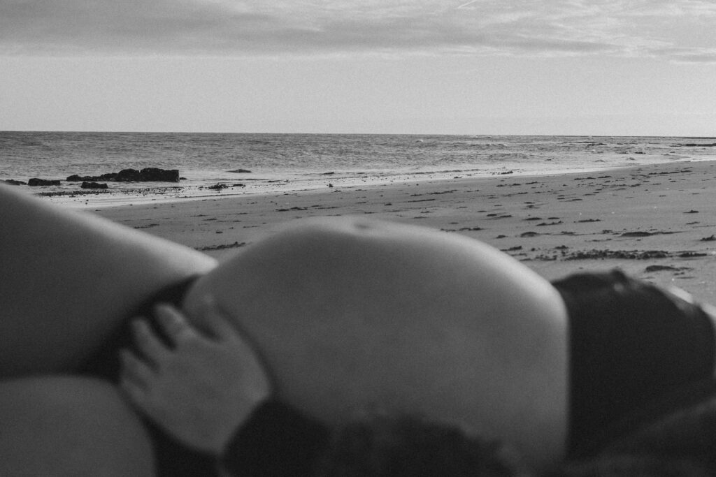Bump shoot with pregnant mother on the beach for professional pregnancy shoot in Margate at Botany Bay lying down on the sand with the sunset captured by Naomi Gale