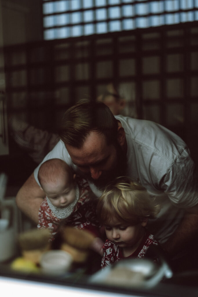 Margate family portrait shoot with a family by the sink in the kitchen captured through the window