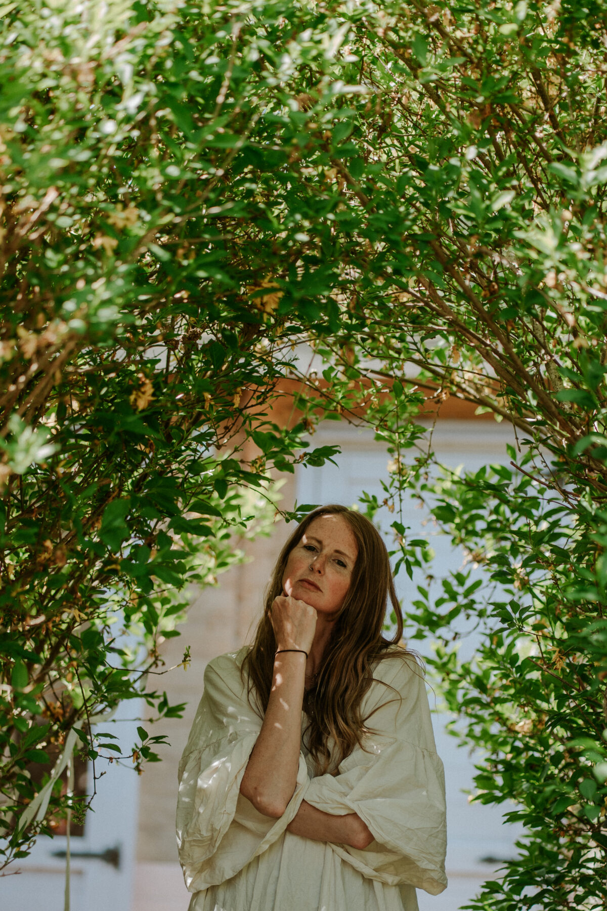 Naomi gently touching her abdomen in a natural setting, representing womb healing and somatic body care rituals from the holistic pelvic floor healing course.